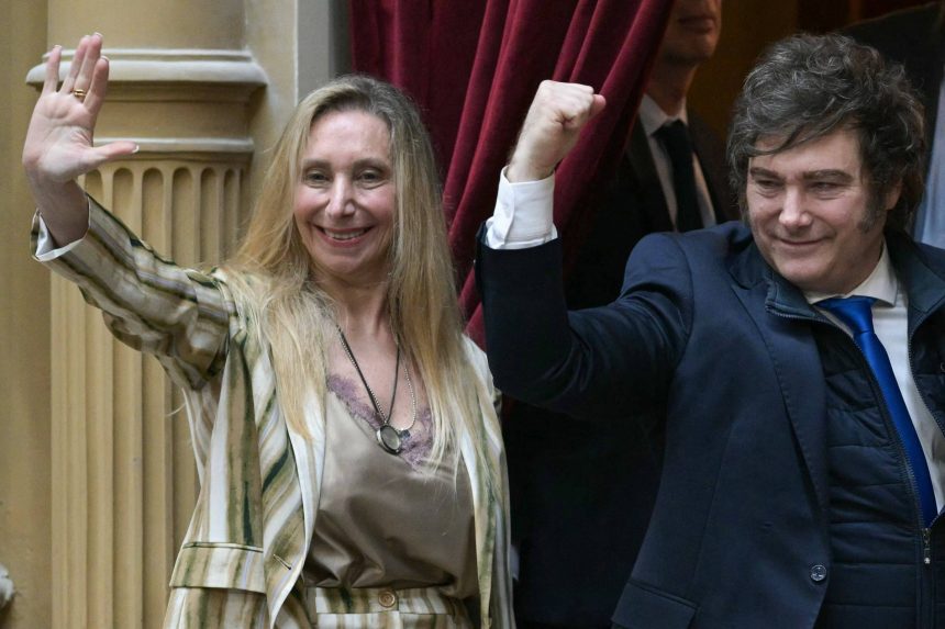 Javier Milei ao lado de Karina Milei diante de cortina vermelha